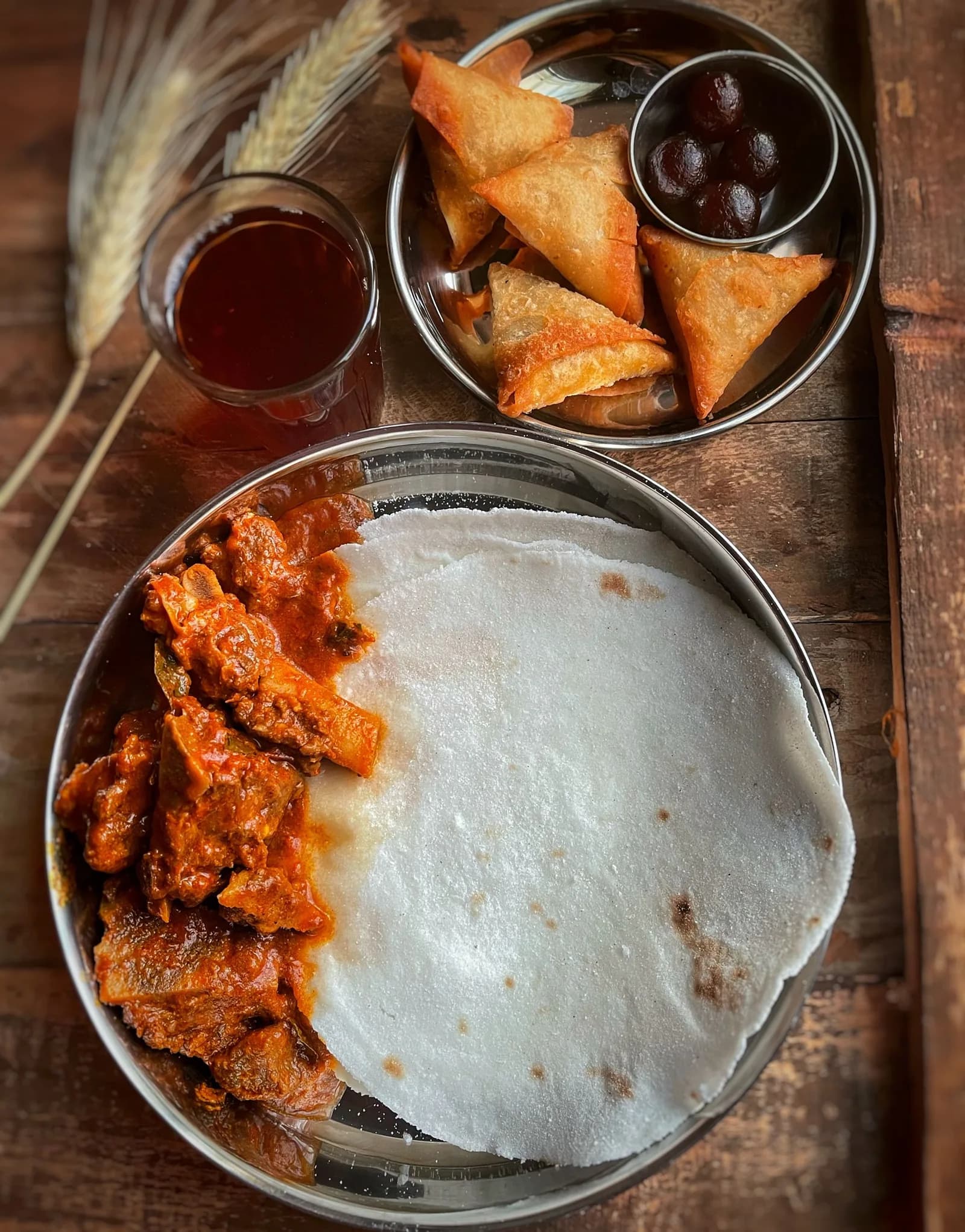 Appam on a steel plate with a bowl of chicken stew.