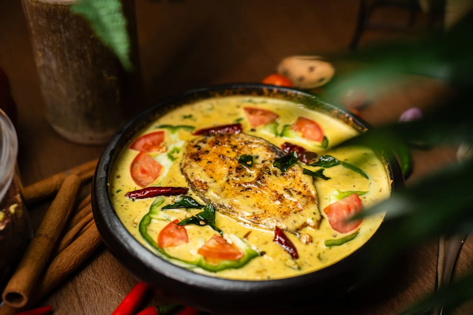 Coconut fish curry in a creamy yellow gravy with tomato, green chilli and curry leaves.